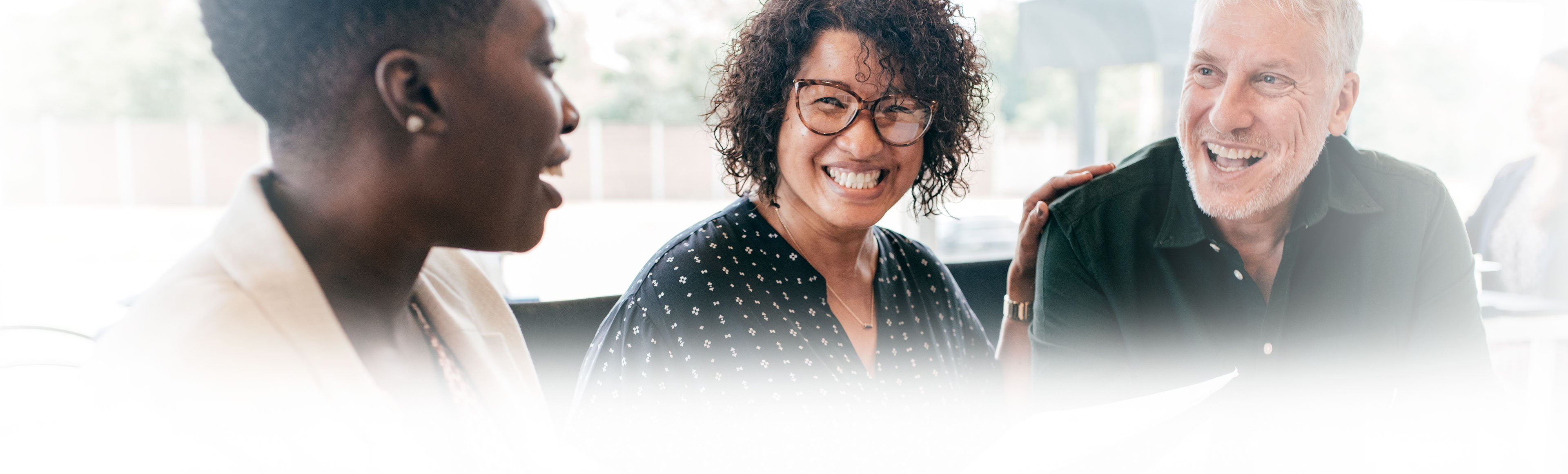 Three adults smiling at one another 